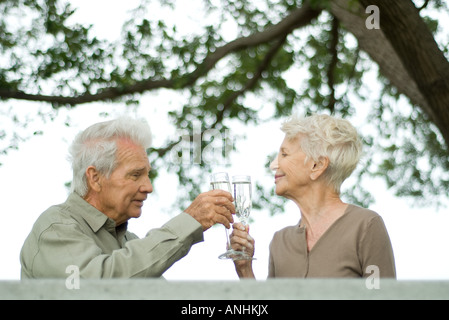Coppia senior fare un brindisi con champagne all'aperto Foto Stock