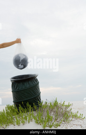 Persona in possesso di globo in un sacchetto di plastica sopra l'immondizia, vista ritagliata Foto Stock