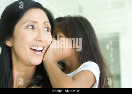 Ragazza whispering in madre l orecchio, close-up Foto Stock