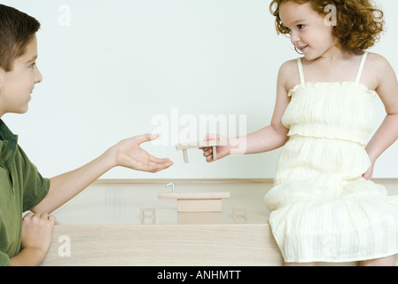 Ragazzo e sorellina giocando con blocchi, ragazza consegna pezzo al fratello Foto Stock