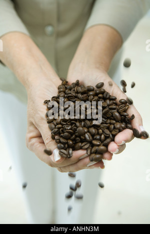 Donna di mani tenendo i chicchi di caffè, ritagliato Foto Stock