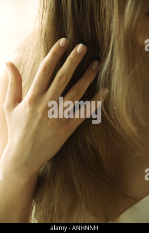Giovane donna di toccare i capelli, vista ritagliata della mano Foto Stock