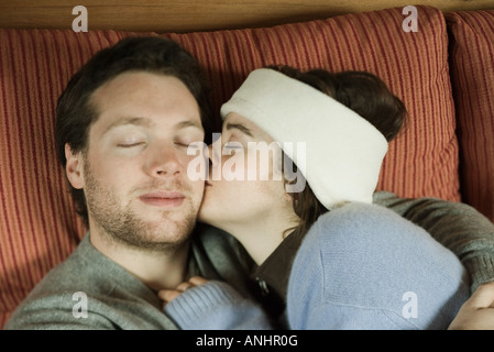Coppia giovane sdraiata su lettino, donna uomo bacio sulla guancia a occhi chiusi Foto Stock
