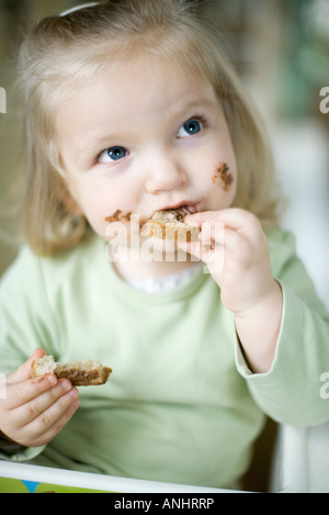 Bionda ragazza toddler mangiare pane al cioccolato Foto Stock