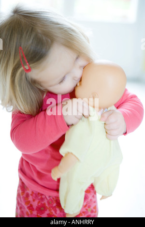 Blonde toddler ragazza baciare baby doll Foto Stock