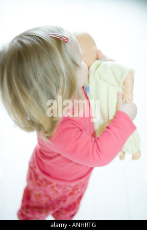 Blonde toddler girl holding baby doll Foto Stock