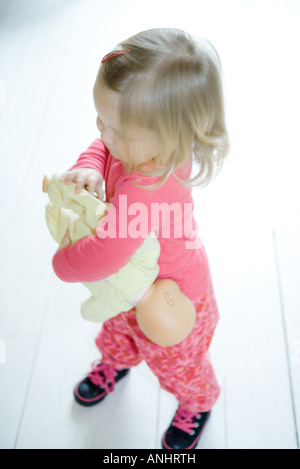 Blonde toddler girl holding baby doll capovolto Foto Stock