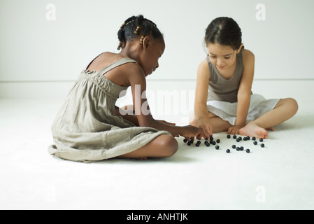 Due ragazze seduto per terra giocando con marmi Foto Stock