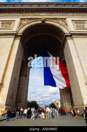 Parigi, il monumento all'Arco di Trionfo. Turisti in folle sull'Etoile Rond Point des Champs Elysees e tricolore in volo. Francia Foto Stock