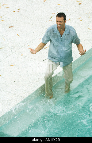 L'uomo spruzzi in piscina, completamente vestito, ad alto angolo di visione Foto Stock