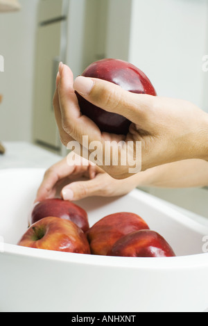 La donna accanto alla coppa di frutta, azienda Apple in mano, vista ritagliata Foto Stock