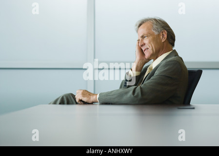 Imprenditore seduto, tenendo la testa, guardando lontano Foto Stock