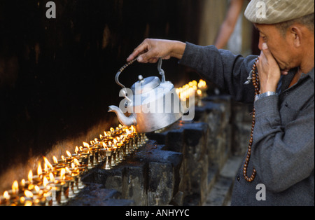 Pellegrino buddista tibetano con mala che si abbina alle tradizionali lampade al burro al tempio di Mahabodhi durante il Festival di Kalachakra. Bodh Gaya, Bihar. India Foto Stock