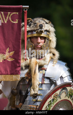 Un reenactor vestito come un centurione romano e tenendo un legionnary standard, Chedworth, Gloucestershire, Regno Unito Foto Stock