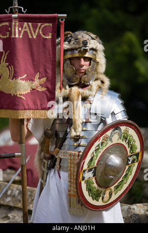 Un reenactor vestito come un centurione romano e tenendo un legionnary standard, Chedworth, Gloucestershire, Regno Unito Foto Stock