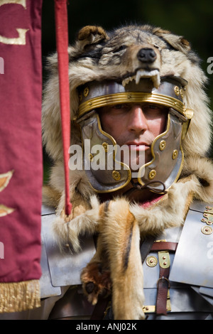 Un reenactor vestito come un centurione romano e tenendo un legionnary standard, Chedworth, Gloucestershire, Regno Unito Foto Stock