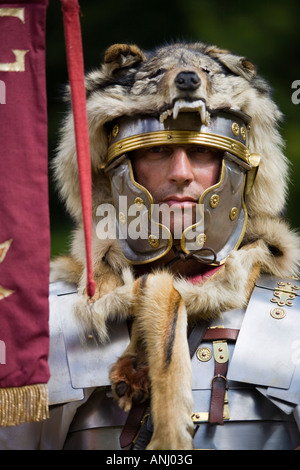 Un reenactor vestito come un centurione romano e tenendo un legionnary standard, Chedworth, Gloucestershire, Regno Unito Foto Stock