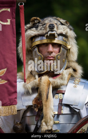 Un reenactor vestito come un centurione romano e tenendo un legionnary standard, Chedworth, Gloucestershire, Regno Unito Foto Stock