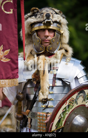 Un reenactor vestito come un centurione romano e tenendo un legionnary standard, Chedworth, Gloucestershire, Regno Unito Foto Stock