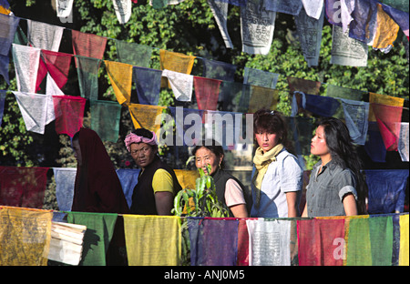 Pellegrini buddisti tibetani, tradizionali e moderni, che circumambulano il Tempio Mahabodhi nei giardini disseminati di bandiere di preghiera. Bodh Gaya, India Foto Stock