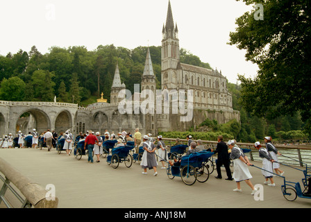 Un lavoratore sgombra i resti di bruciato candele accese dai pellegrini in preghiera e speranza a Lourdes, Francia Foto Stock