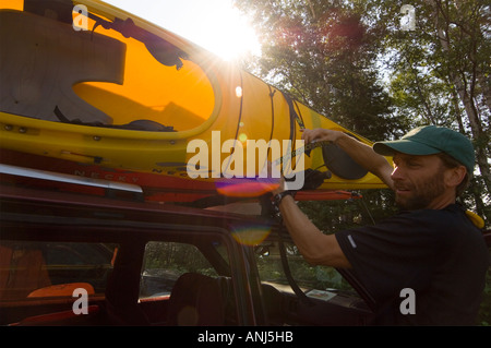 Un KAYAKER prende un kayak di colore giallo al di fuori della sua vettura RACK Foto Stock