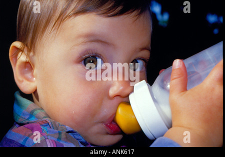 Baby grandi occhi di bere latte e guardando la fotocamera. Foto di Willy Matheisl Foto Stock