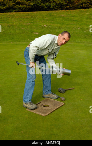 Capo verde-keeper rendendo il nuovo foro sul campo da golf di colore verde. Foto Stock