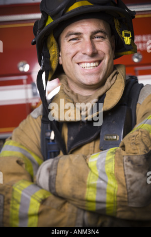 Close up di un vigile del fuoco sorridente con le braccia incrociate Foto Stock