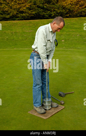 Head Green Keeper rendendo il nuovo foro sul campo da golf di colore verde. Foto Stock