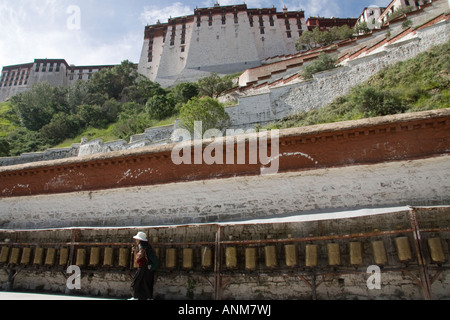 Una donna tibetana a piedi lungo le ruote della preghiera dietro il palazzo del Potala a Lhasa il Tibet Foto Stock