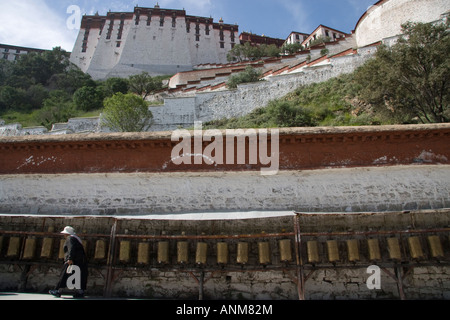 Una donna tibetana a piedi lungo le ruote della preghiera dietro il palazzo del Potala a Lhasa il Tibet Foto Stock