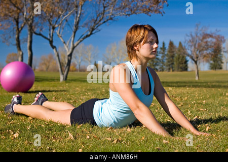 La donna posa su erba facendo un prolungamento posteriore Foto Stock