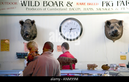 Uomo e bambino shopping presso le macellerie con ripieni di verri" teste e orologio a Borough Market Foto Stock