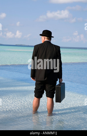 Maldive surriscaldamento imprenditore occidentale vestita in Bowler cappello e business suit si fermò in piscina Foto Stock