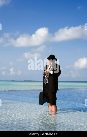 Maldive surriscaldamento imprenditore occidentale vestita in Bowler cappello e business suit controllo orologio Rolex si fermò in piscina Foto Stock