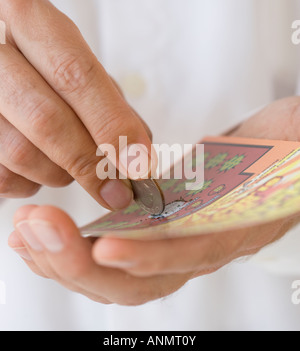 Uomo di graffiare la scheda di lotteria con moneta Foto Stock