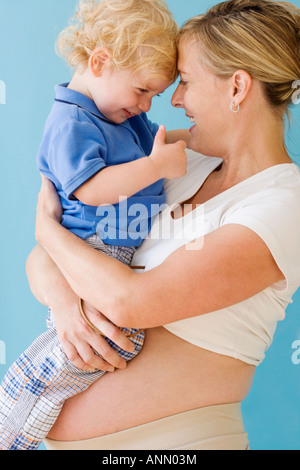 Donna incinta abbracciando il bambino Foto Stock