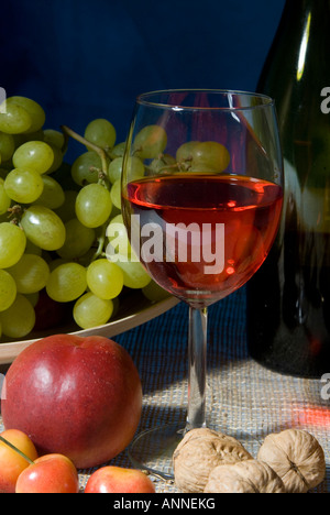 Classic still life con una colorata ciotola di frutta e una bottiglia di vino con un wineglasses su sfondo nero Foto Stock