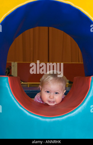 Ritratto verticale di un grazioso Caucasian Baby girl playing peek-a-boo sul morbido blocchi di costruzione a un bambino piccolo gruppo Foto Stock