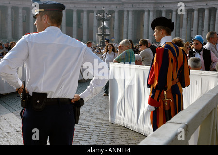 In attesa del papa a Roma a Piazza San Pietro una guardia svizzera e un poliziotto vegliare sull'enorme folla Foto Stock