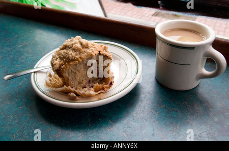 Forcella e in parte mangiato muffin su una piastra e una tazza di caffè in un bar Foto Stock