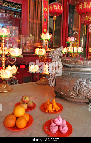 Altare in un tempio cinese con varie offerte e delle candele Foto Stock