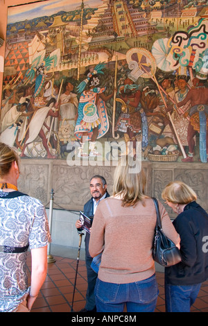 Una guida turistica che mostra ai turisti un murale dipinto da Diego Rivera presso il Palazzo Nazionale a Città del Messico MESSICO Foto Stock