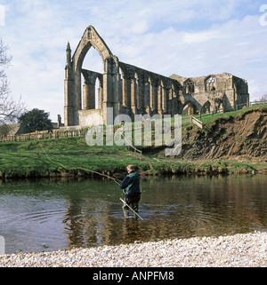 Bolton Abbey rovina di Agostino Priory noto anche come Bolton Priory & man di pesca a mosca nel fiume Wharfe Wharfedale North Yorkshire Dales England Regno Unito Foto Stock