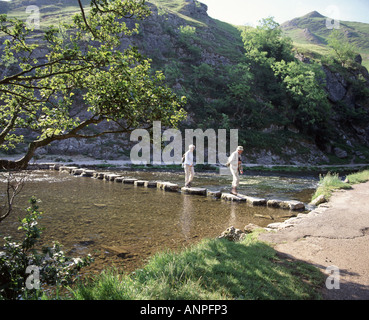 Walkers Varcando il fiume Colomba pietre miliari nella Dovedale Peak District Foto Stock