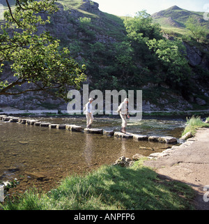 Walkers Varcando il fiume Colomba pietre miliari nella Dovedale Peak District Foto Stock