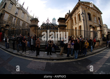 I turisti giapponesi in piedi nella parte anteriore del Sheldonian Theatre Clarendon Building e la Libreria di Bodleian Oxford Foto Stock