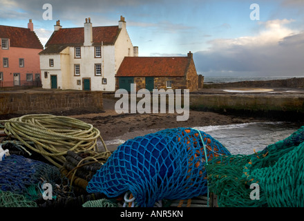 Le reti da pesca ammucchiate sul quay con magazzini in background a Pittenweem Scozia Scotland Foto Stock