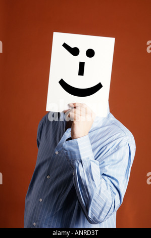 Uomo in possesso di una carta con un emoticon winking faccia Foto Stock